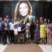 Autoridades, familiares e convidados posam em cerimônia na Câmara de Itararé em homenagem a Raquel de Oliveira Lima, com imagem da homenageada projetada ao fundo.